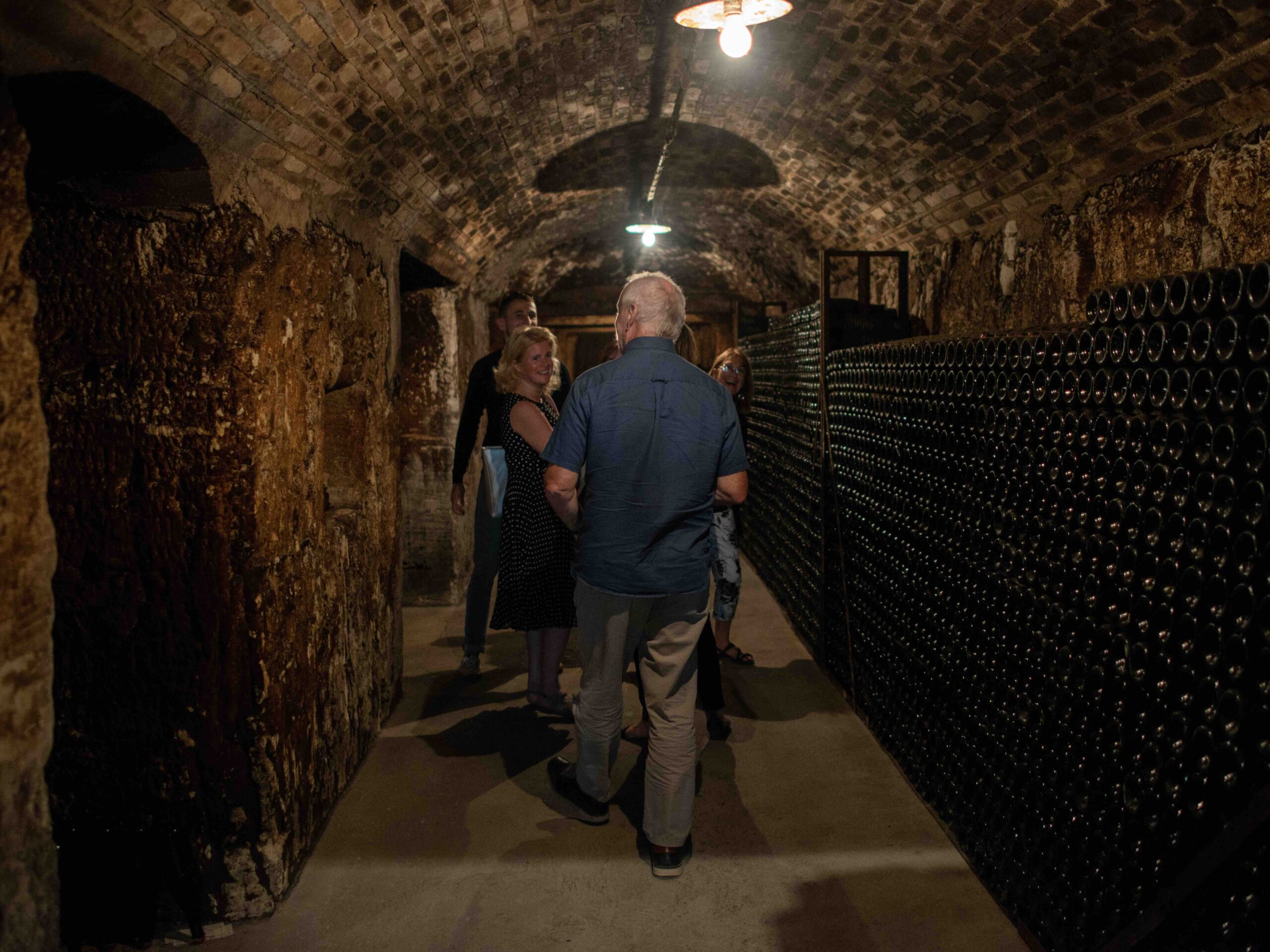 Champagne Cellar Visit – Day Trip from Paris Small group on a guided walk through historic Champagne cellars lined with aging bottles on a private day trip from Paris