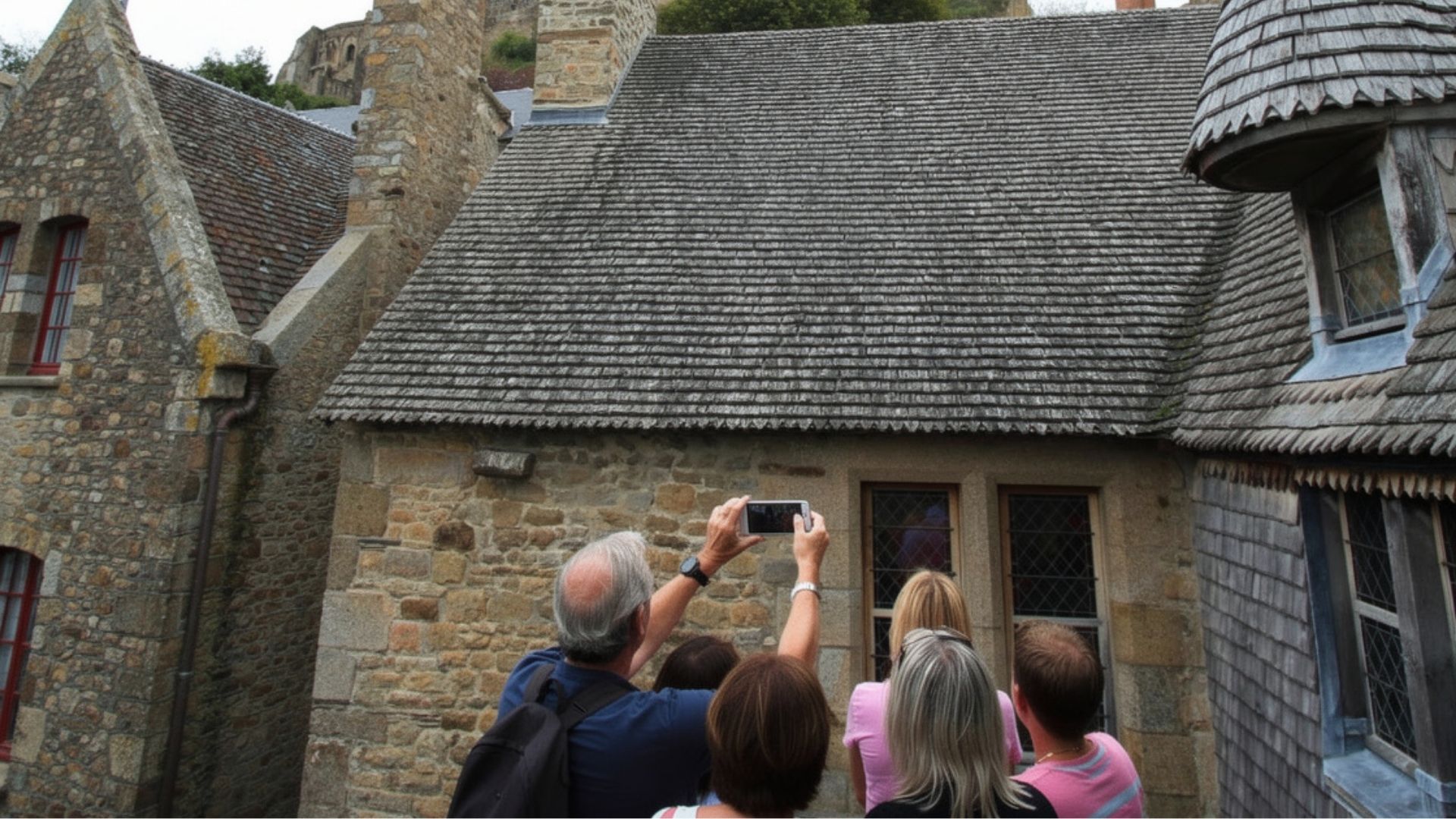 Mont Saint-Michel Medieval Architecture Paris and Beyond Tours Family Normandy Tour Paris and Beyond Tours family group photographing Mont Saint-Michel medieval stone buildings with traditional slate roofs - private Normandy architecture tour from Bayeux Caen