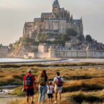 Family walking tidal flats Mont Saint-Michel golden hour sunset low tide - Paris and Beyond Tours private tour from Bayeux Caen